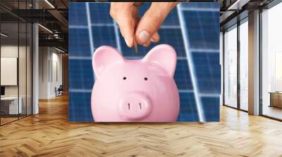 Unrecognizable manager putting coin into piggy bank while saving money near photovoltaic panel on solar farm Wall mural