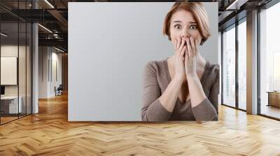 Worried woman holding face with hands on background Wall mural