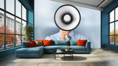 Young businessman talking on the megaphone on background Wall mural