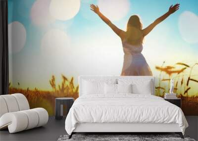 Young woman on field under sunset light Wall mural