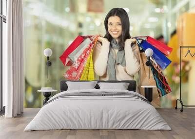 Young woman with shopping bags on  background Wall mural