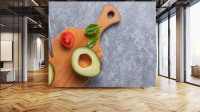 Ripe avocado cut for two parts with cherry tomato and knife on wooden board Wall mural