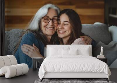 Happy grandmother hugging her young granddaughter on the couch Wall mural