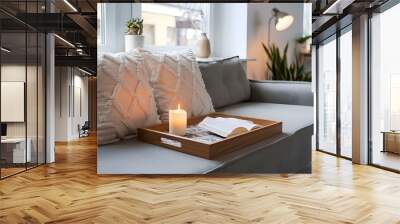 A Scandinavian interior designed modern living room with a stylish and cozy reading nook. A sofa against a window with a wooden tray on top of two decorative pillows and a burning candle. Wall mural