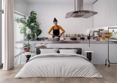 Brunette woman cooking a recipe from a digital tablet in a modern kitchen Wall mural