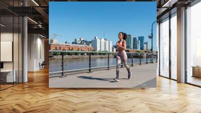 Latin American woman with a pink outfit jogging in Puerto Madero, Buenos Aires Wall mural