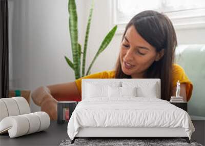 Woman wrapping handmade craft gifts on the table at home Wall mural