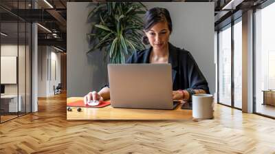 Young woman working online at home with laptop and documents Wall mural