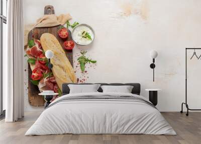 Fresh crispy baguette deli sandwich with prosciutto, tomatoes and arugula. Wall mural