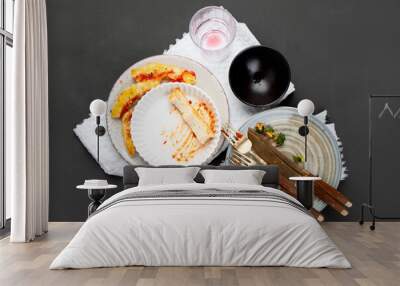 Pile of empty and dirty plates with food leftovers on dark background. Wall mural