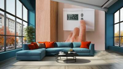 Male hand pushing the button of home heating and cooling system control unit Wall mural