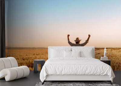 Proud happy victorious wheat farmer with hands raised in V Wall mural