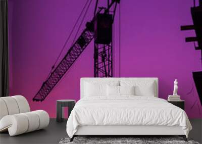 Silhouette of construction crane machinery in purple sunset Wall mural