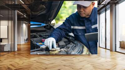 Asian automobile mechanic repairman wearing uniform and protection glove repairing a car engine automotive workshop with tablet, car service and maintenance, Repair service. Wall mural