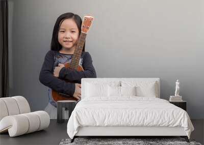 Little asian child play the ukulele, gray background Wall mural