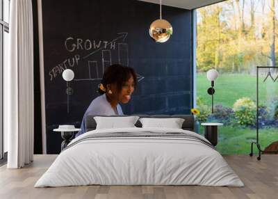 Businesswoman presenting growth strategy on a blackboard in a modern office setting surrounded by nature. Wall mural