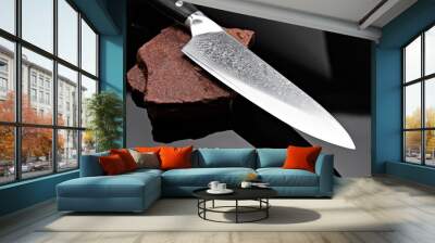 A large kitchen knife with a black handle on a dark background. Knife with a wide sharp blade. Scratched steel surface of the knife blade.  Wall mural