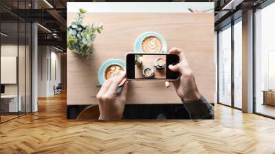 Unrecognizable hands taking a aerial shot of two cups of coffee in a hipster cafe Wall mural