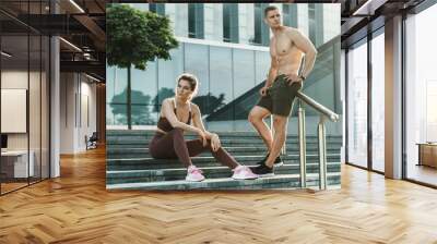 Beautiful fitness couple are posing on a city street Wall mural