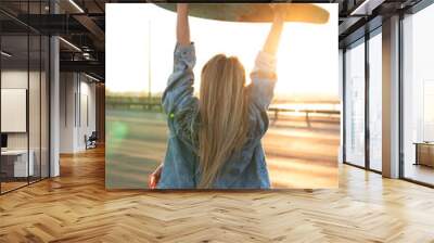 Carefree woman with a longboard on a bridge at sunset Wall mural