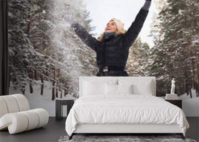 Cheerful woman throwing snow into the air during cold winter day Wall mural