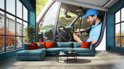 Delivery man with a tablet pc in his van Wall mural