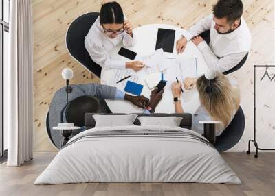 Multi-ethnic business people during meeting in modern office sitting at the round table Wall mural