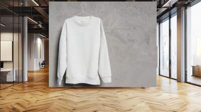 White sweatshirt hanging on the thin metallic hanger against a concrete wall Wall mural