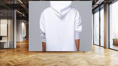 Woman dressed in a white oversized hoodie with blank space, ideal for a mockup, set against gray background Wall mural