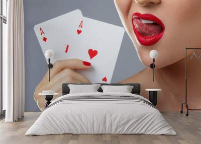 Woman with red lips is holding two aces. Wall mural