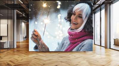 Young happy woman with sparklers in the winter snowy forest Wall mural