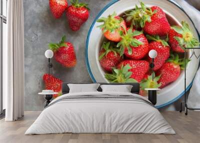 high quality photo. Close-up of vibrant organic strawberries in a white dish with a blue trim, set on a muted gray background. Wall mural