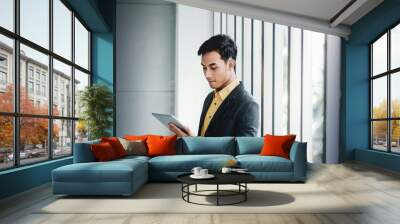 Portrait of Happy Businessman Standing by the Window in Office. Using Digital Tablet and Smiling Wall mural