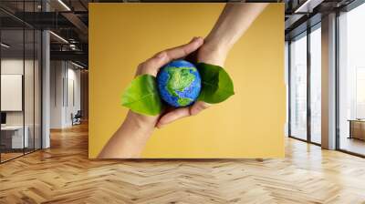 World Earth Day Concept. Green Energy, ESG, Renewable and Sustainable Resources. Environmental and Ecology Care. Hands of People  Embracing Green Leaf and Handmade Globe Wall mural