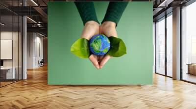 World Earth Day Concept. Green Energy, ESG, Renewable and Sustainable Resources. Environmental and Ecology Care. Hands of Person  Embracing Green Leaf and Craft Globe Wall mural