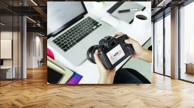 photographer checking dslr camera on desk Wall mural