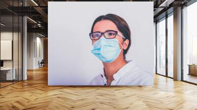 a beautiful young girl puts a surgical mask on her face during a covid-19 pandemic Wall mural