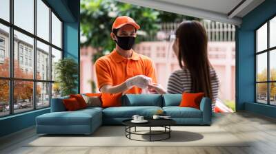 deliveryman in face mask give food to young female customer Wall mural