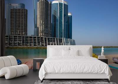 Paddle boards and kayaks on the shore at Reem island in Abu Dhabi, modern glass skyscraper  in the background Wall mural