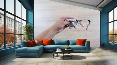 Person Cleaning Black Eyeglasses With Special Wipes Wall mural