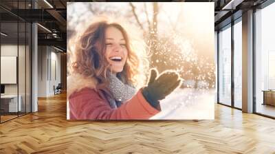 Cheerful girl in warm clothes playing with snow outdoors at sunny winter day. Expressing positivity, true brightful emotions. The concept of portrait in winter snowy weather.  Wall mural