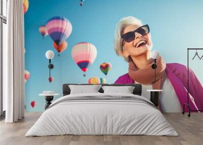 Portrait of a adult pleased woman in her that is wearing a chic cardigan against a colorful balloon festival with hot air balloons in the sky background. Wall mural