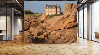 Museum Maison du Littoral towering the extraordinarily beautifully colored stones and fantastically shaped rock formations at sunset- the famous pink granite coast in Brittany, France Wall mural