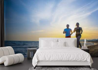 Man and women running on tropical beach at sunset Wall mural