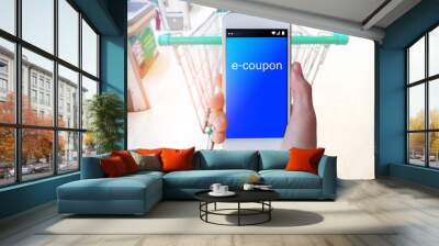 Hand holding mobile phone at supermarket checkout background, e coupon concept Wall mural