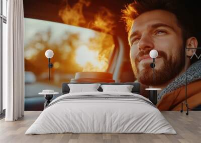 Handsome man drinking coffee while sitting in a car and enjoying the sunset. Wall mural