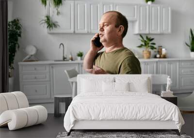 A man with inclusivity wearing casual attire stands in a kitchen and speaks on a phone. Wall mural