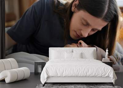 A young gay couple shares a tender moment in their bedroom, showcasing their love and affection. Wall mural