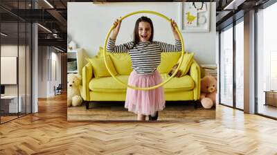 A young girl with a prosthetic leg smiles while playing with a hula hoop in her living room. Wall mural