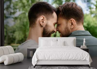 Two bearded gay men in casual attire stand close together in a green park. Wall mural